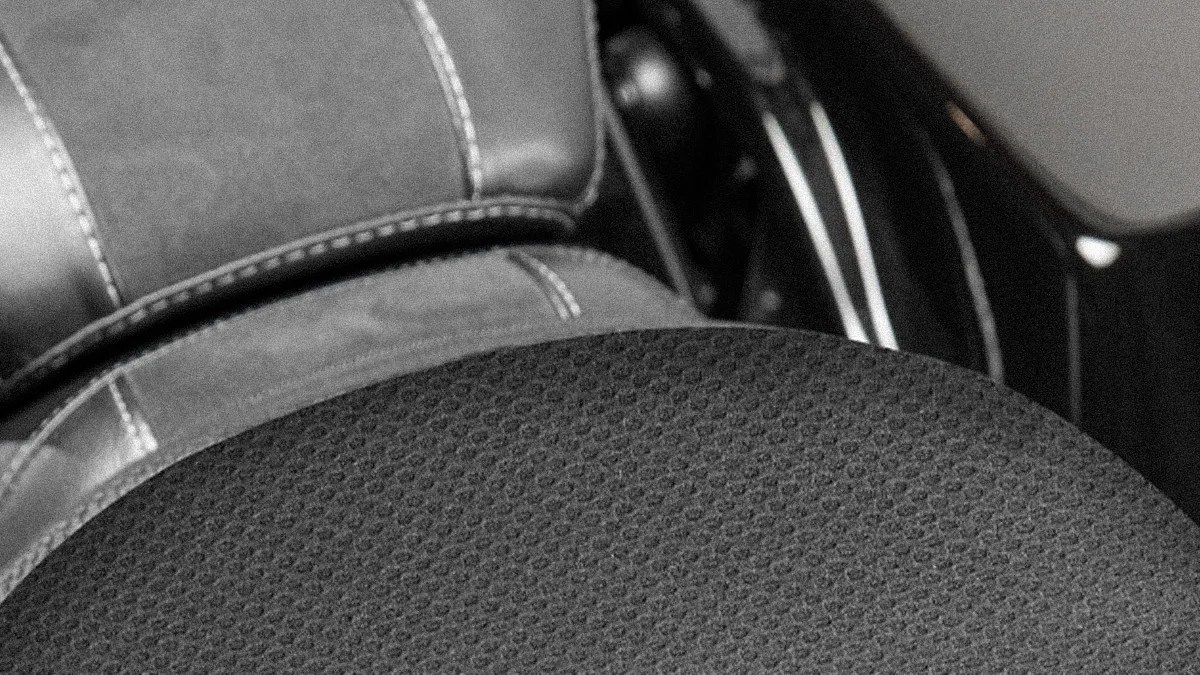 Close-up of a black textured circular seat cushion on a motorcycle seat with visible stitching.