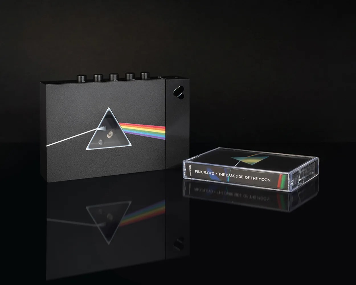 Black cassette player and cassette tape with Pink Floyd "The Dark Side of the Moon" album cover art on a reflective black surface.