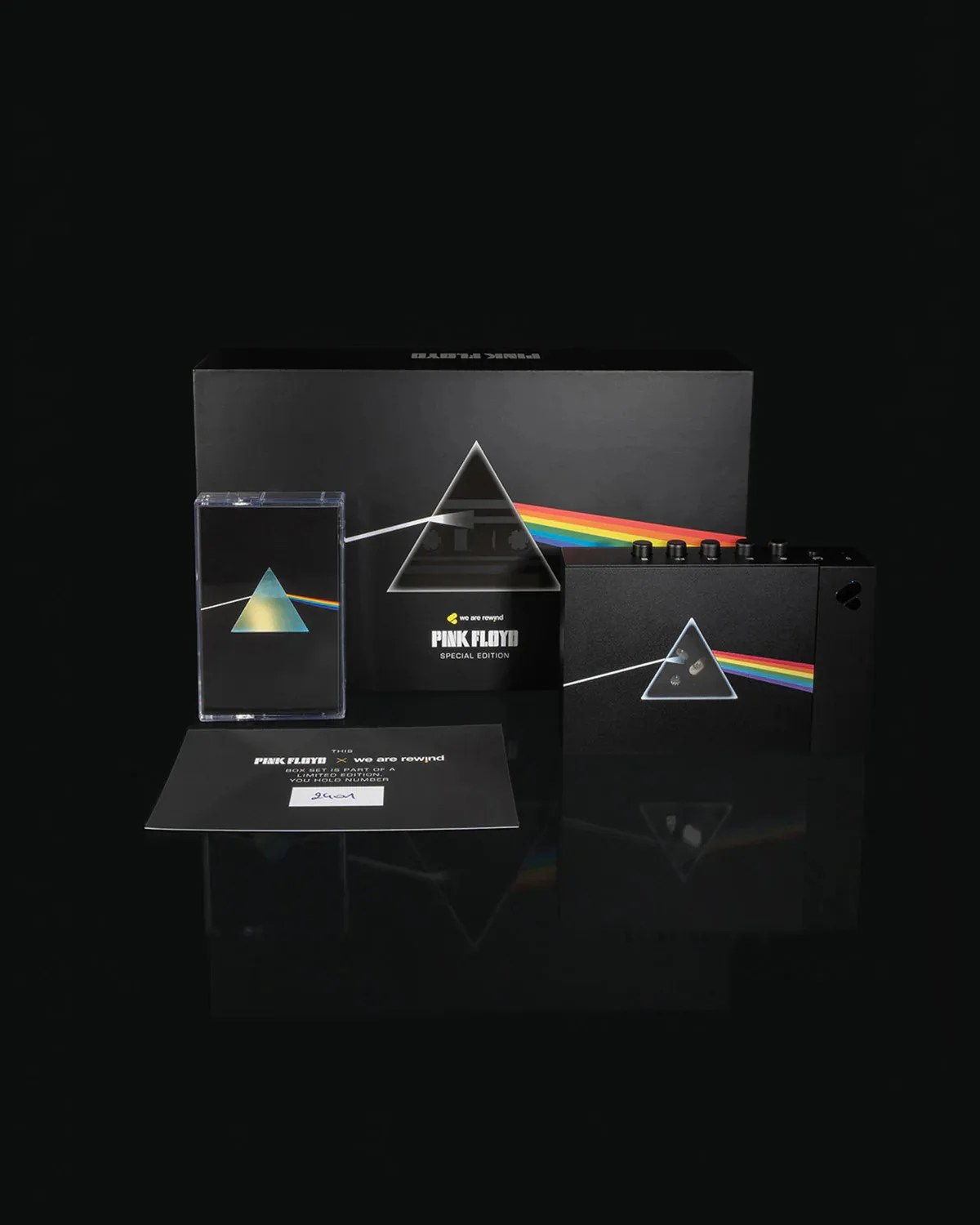 Limited edition Pink Floyd "Dark Side of the Moon" box set including a cassette, a card, and a black device with the iconic prism and rainbow design on a black background.