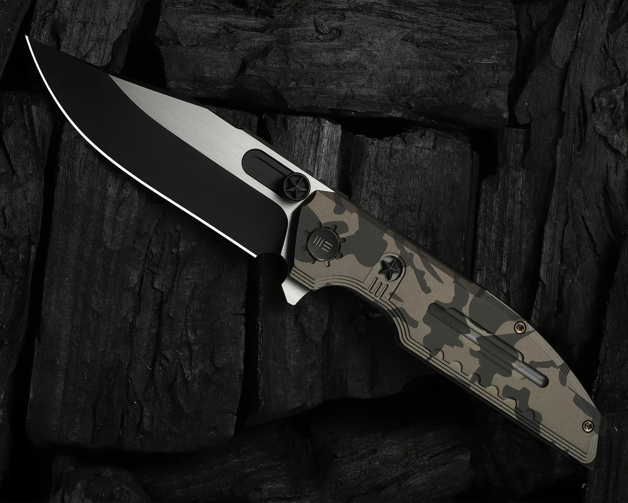 Folding knife with a black and silver blade and a camouflage-patterned handle on dark textured wood.