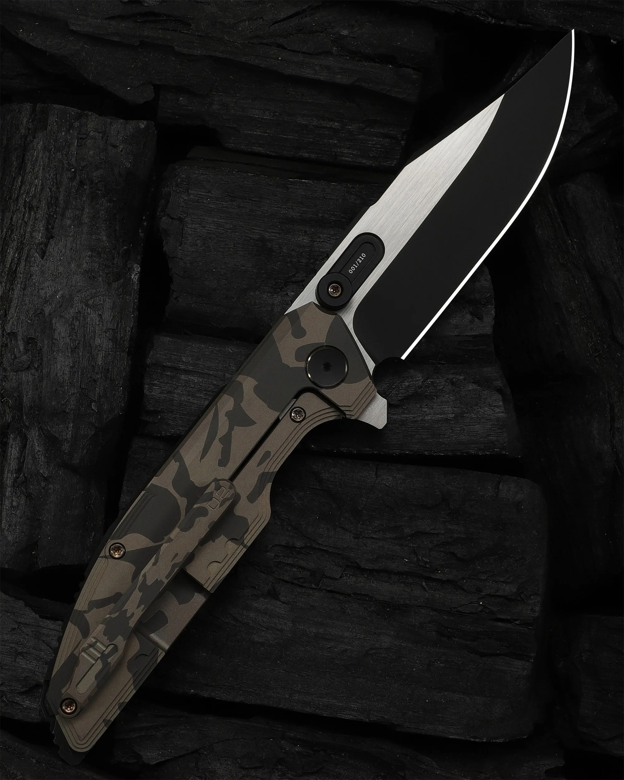 Folding knife with a black and silver blade and a camouflage-patterned handle on black charcoal.