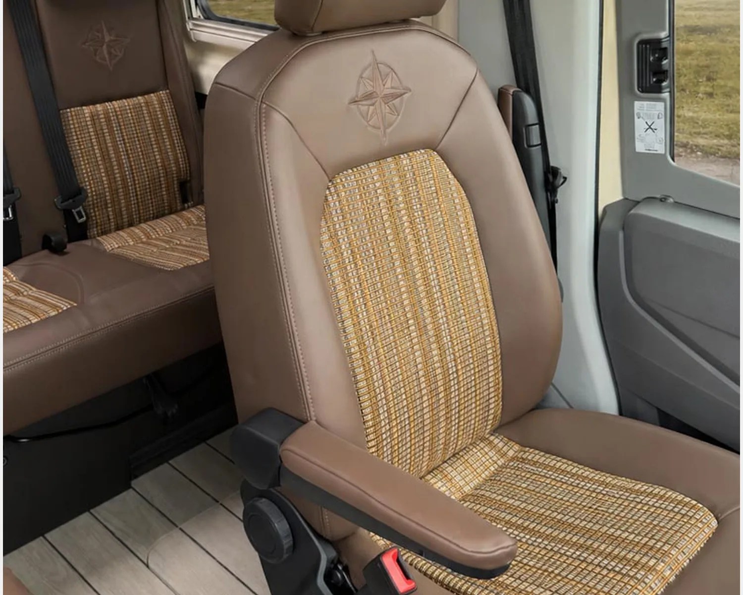 Brown leather car seat with a beige and yellow plaid fabric center and an embossed compass design on the headrest.
