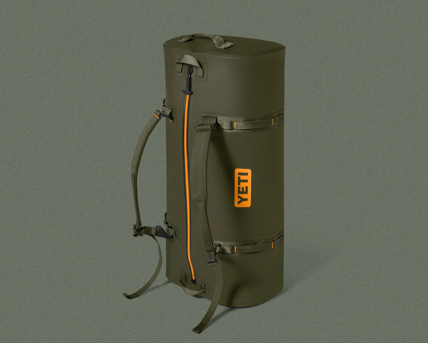 Olive green YETI duffel bag with orange zipper and shoulder straps standing upright.