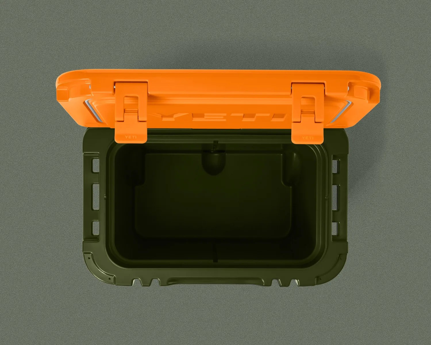 Open dark green cooler with bright orange lid and two latches on a gray surface.
