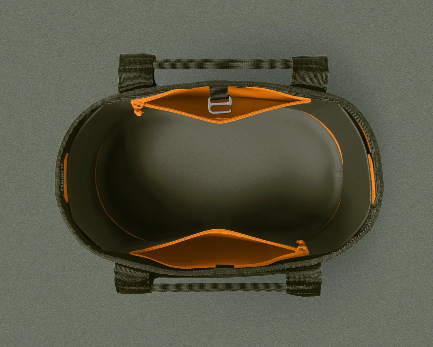 Top view of an empty olive green tote bag with orange interior pockets and black handles on a matching olive green surface.