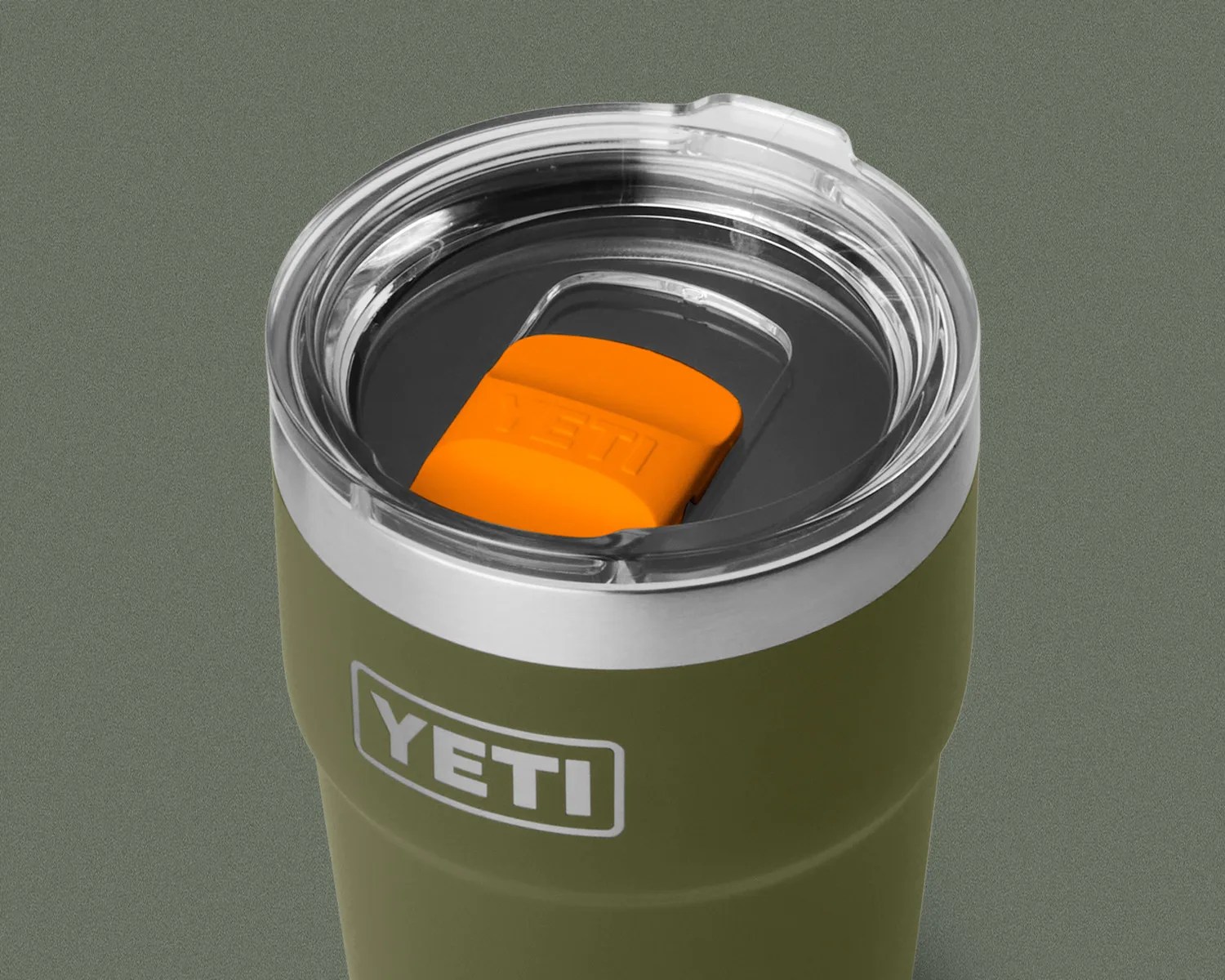 Olive green YETI tumbler with clear lid and orange slider on a gray background.