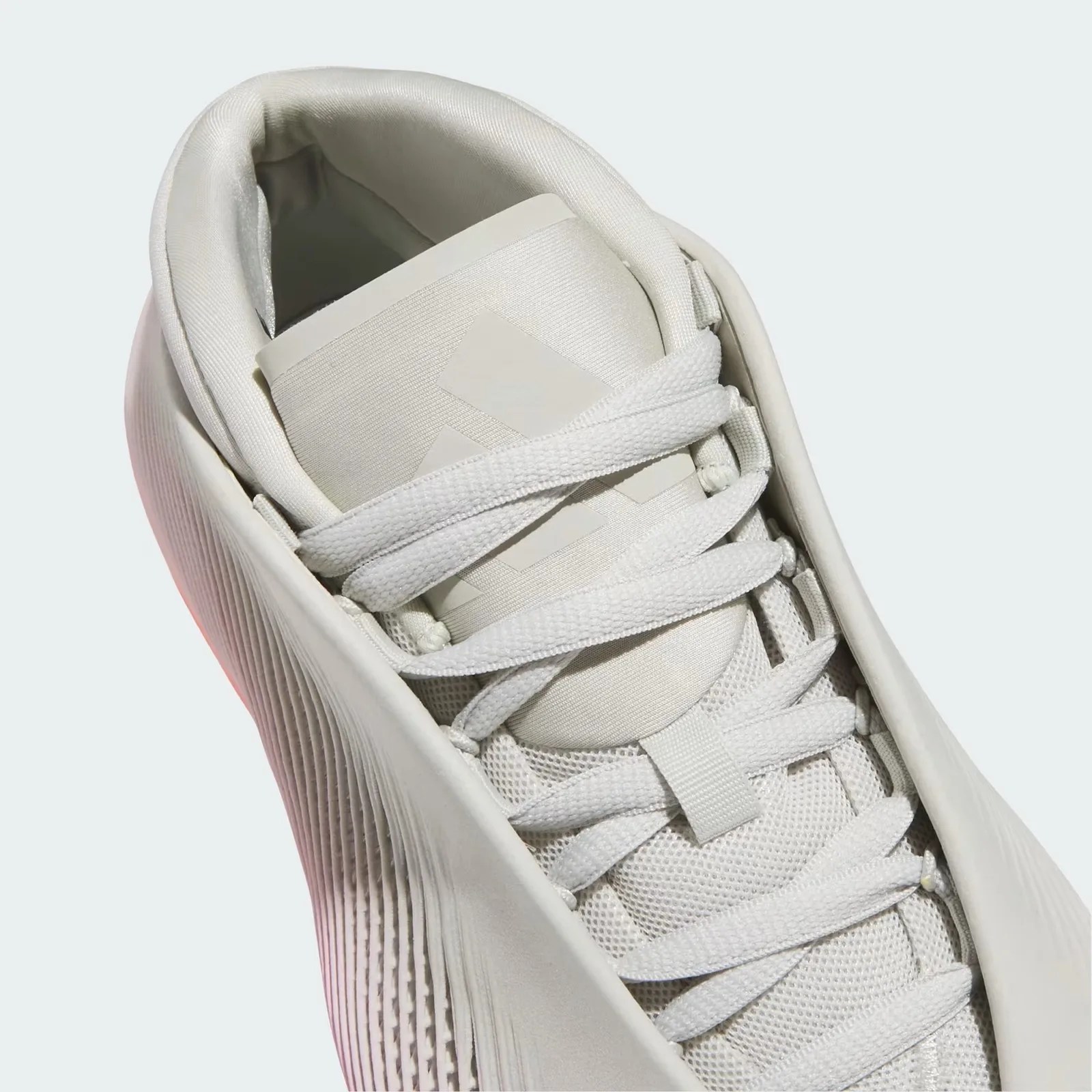 Close-up of a white sneaker with textured side panels, mesh upper, and flat laces.