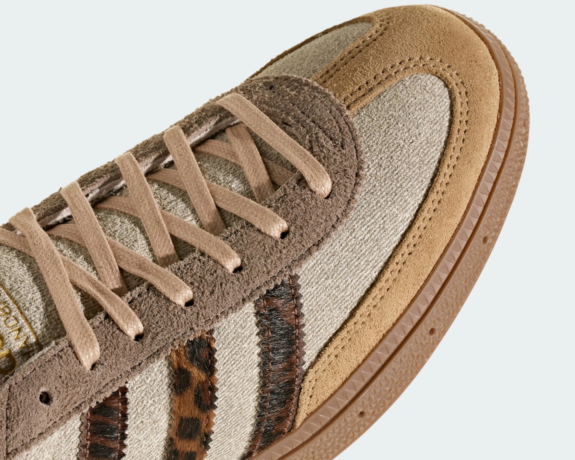 Close-up of a beige and brown suede sneaker with leopard print fabric and tan laces.