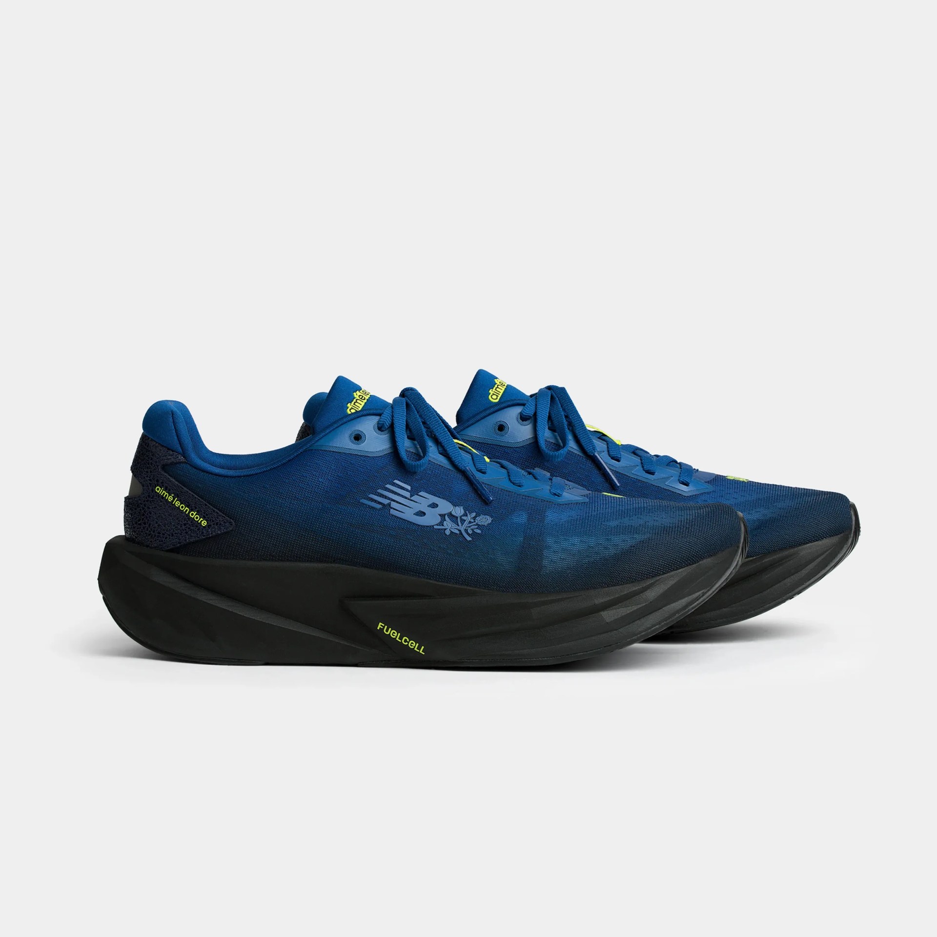 Pair of blue New Balance running shoes with black soles and yellow accents, featuring "aime leon dore" branding.