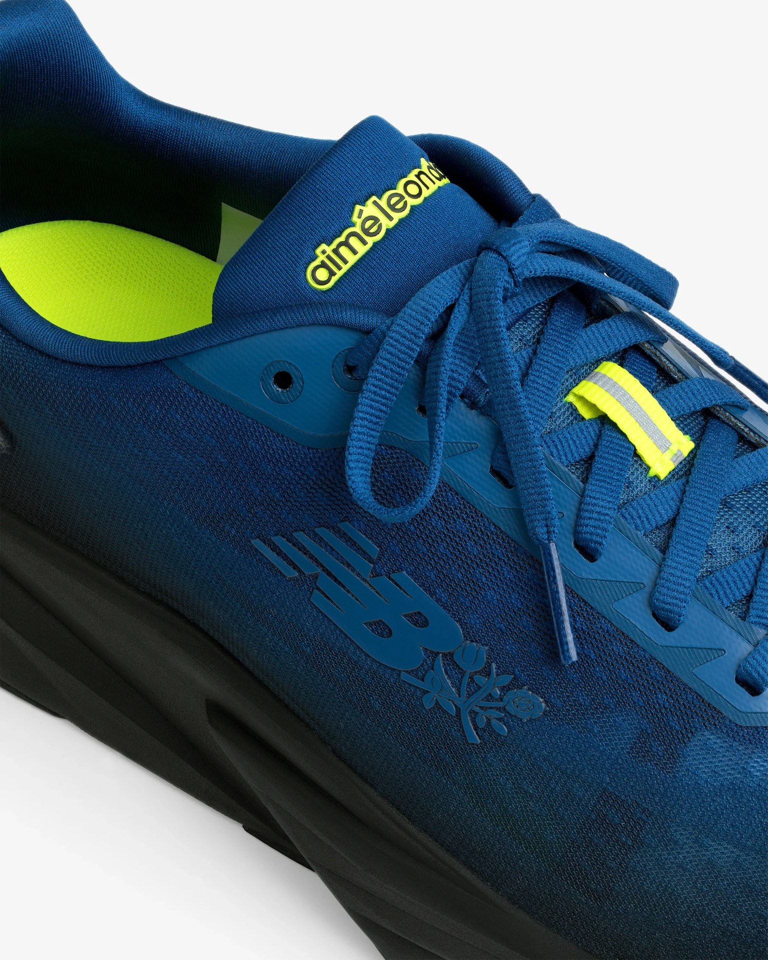 Blue New Balance sneaker with black sole, neon yellow insole, and "aimé leon d" logo on the tongue.