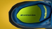 Top view of a blue sneaker with neon green insole featuring "aimé leon dore" and "NB" logos on a yellow background.