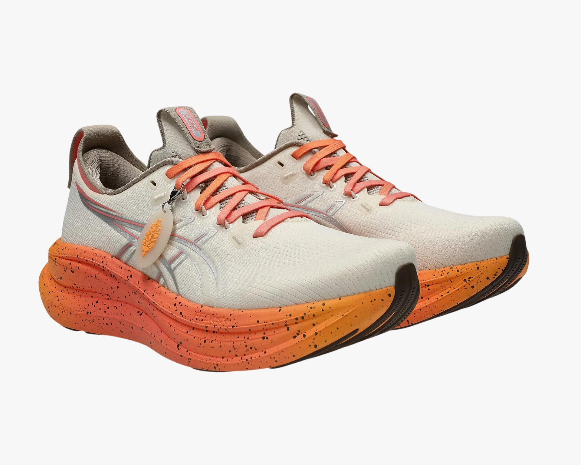 Light beige running shoes with orange gradient speckled soles and orange laces.