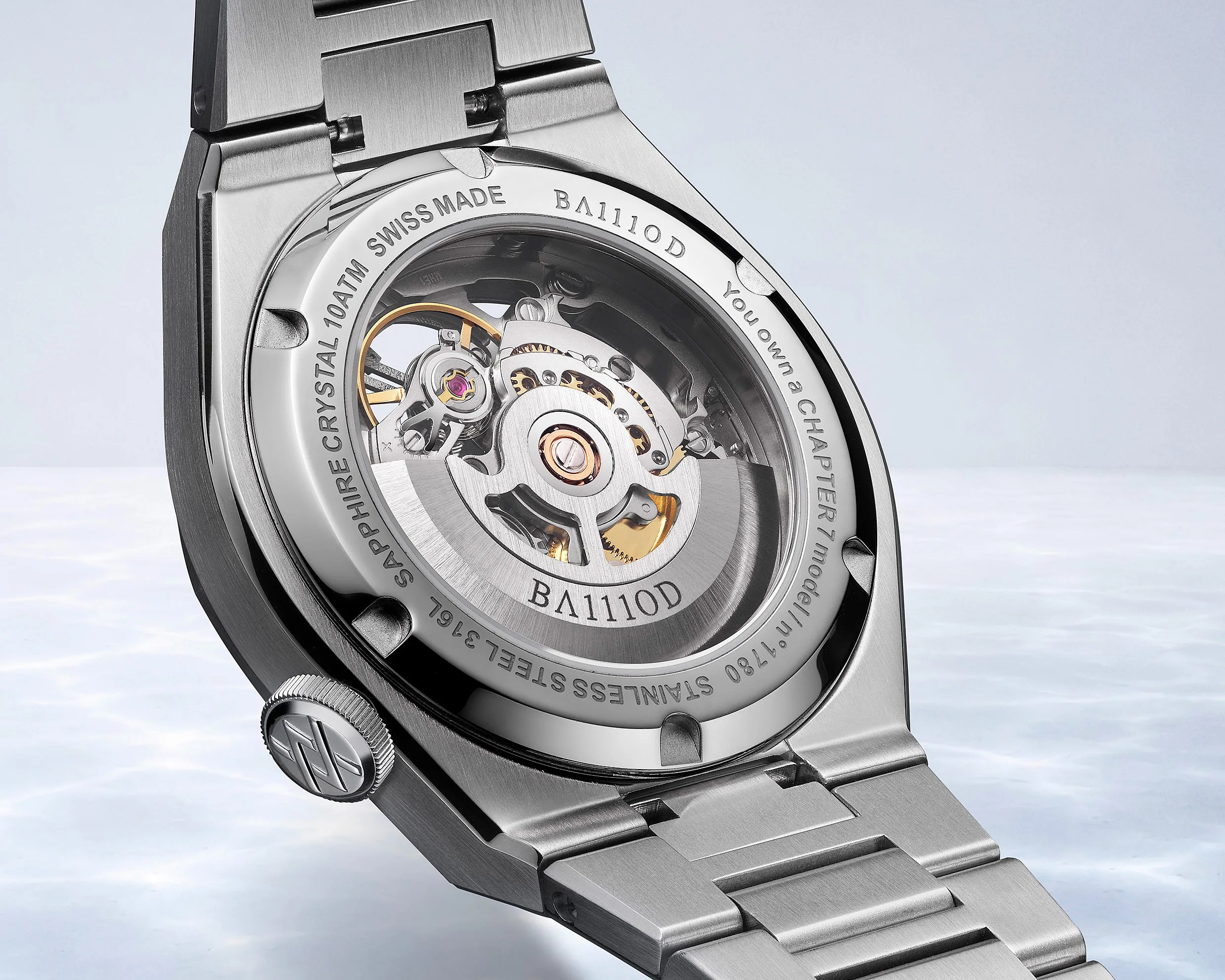 Close-up of a stainless steel wristwatch back showing the mechanical movement through a sapphire crystal case.