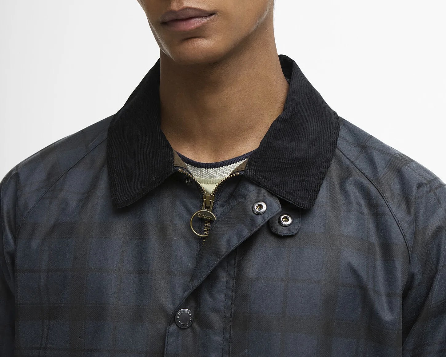 Close-up of a dark plaid jacket with a black corduroy collar and a brass zipper pull ring.