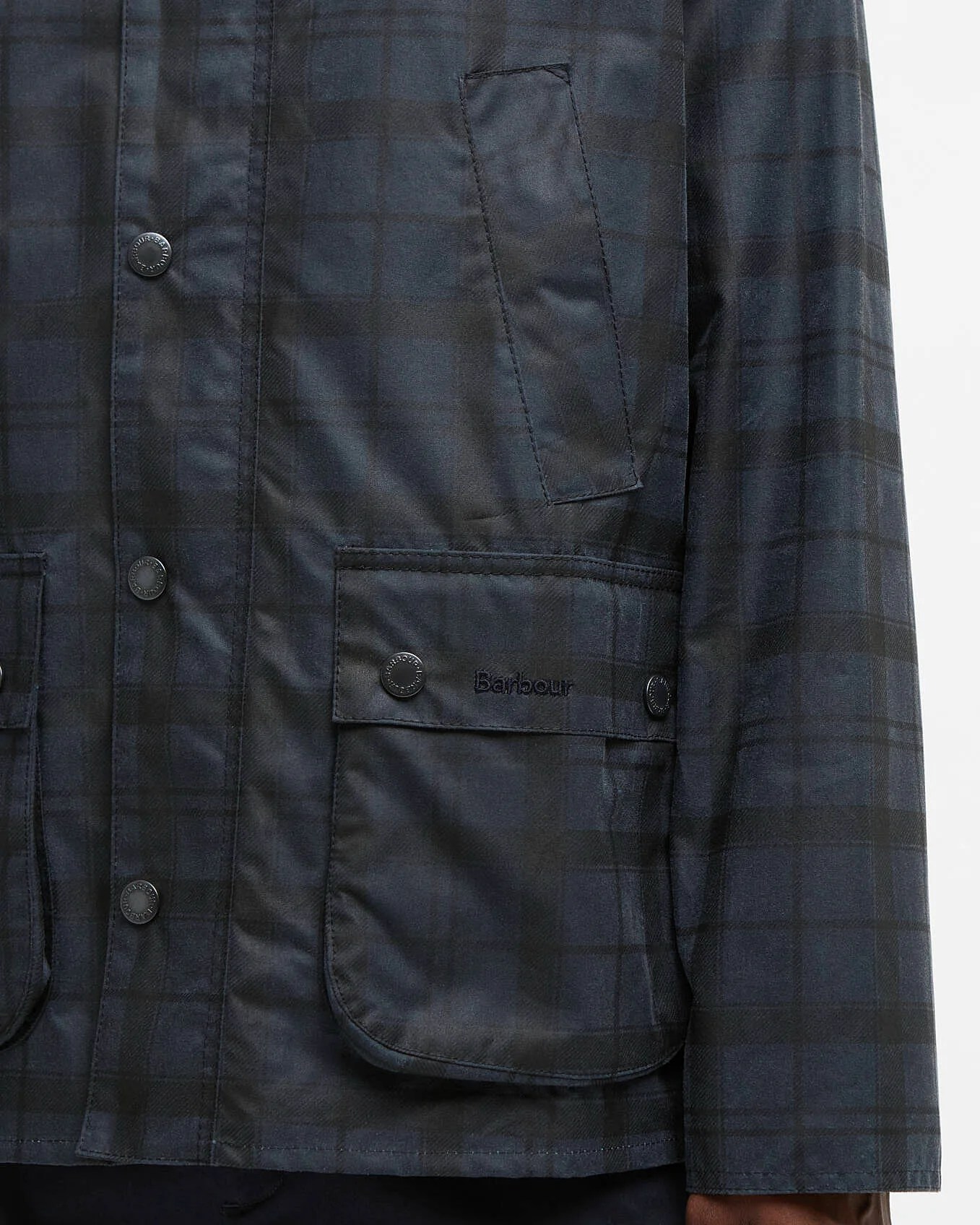 Close-up of a dark blue and black checkered Barbour jacket with snap buttons and flap pockets.