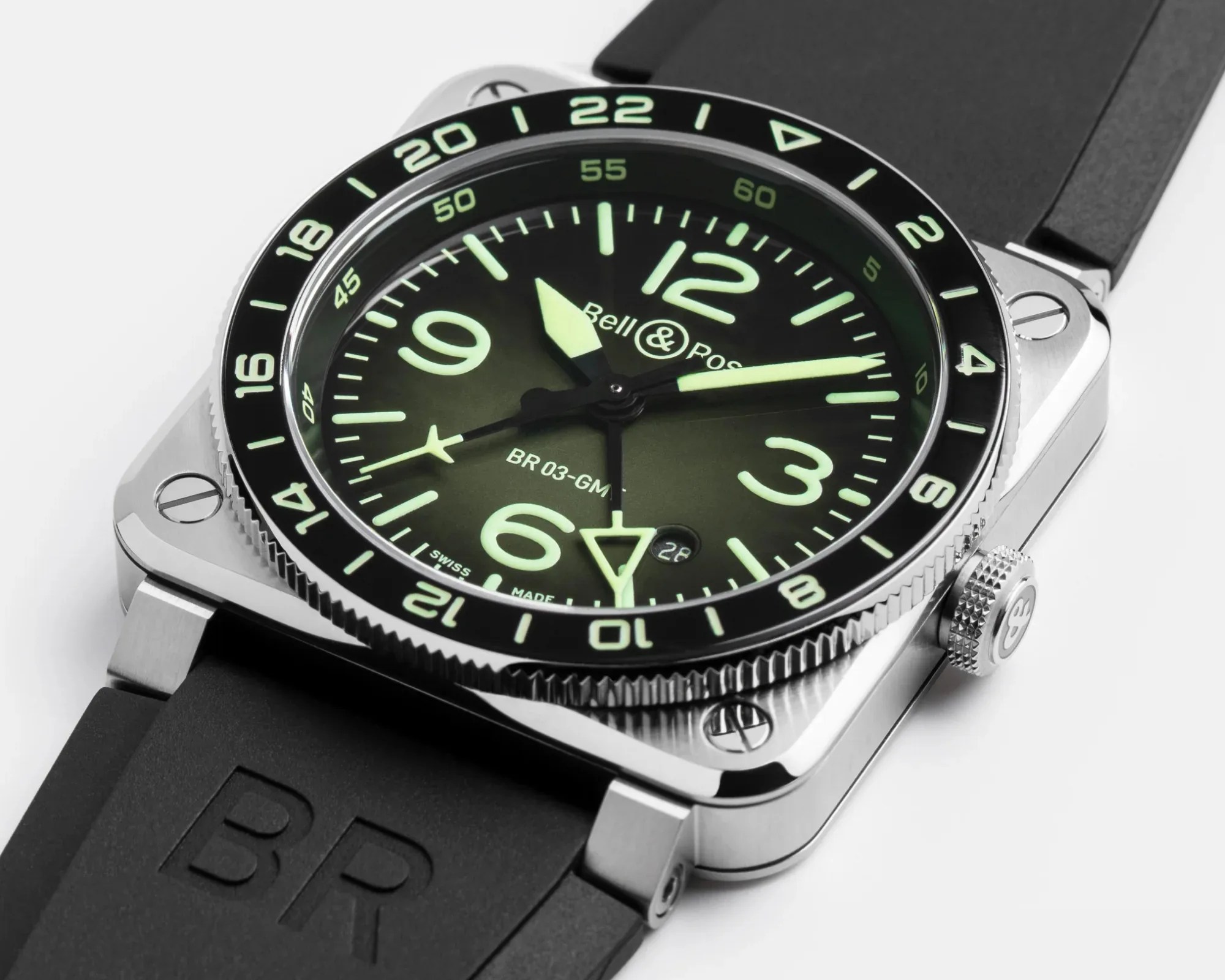 Square stainless steel Bell & Ross BR 03-GMT watch with black dial, luminescent numerals, and black rubber strap.