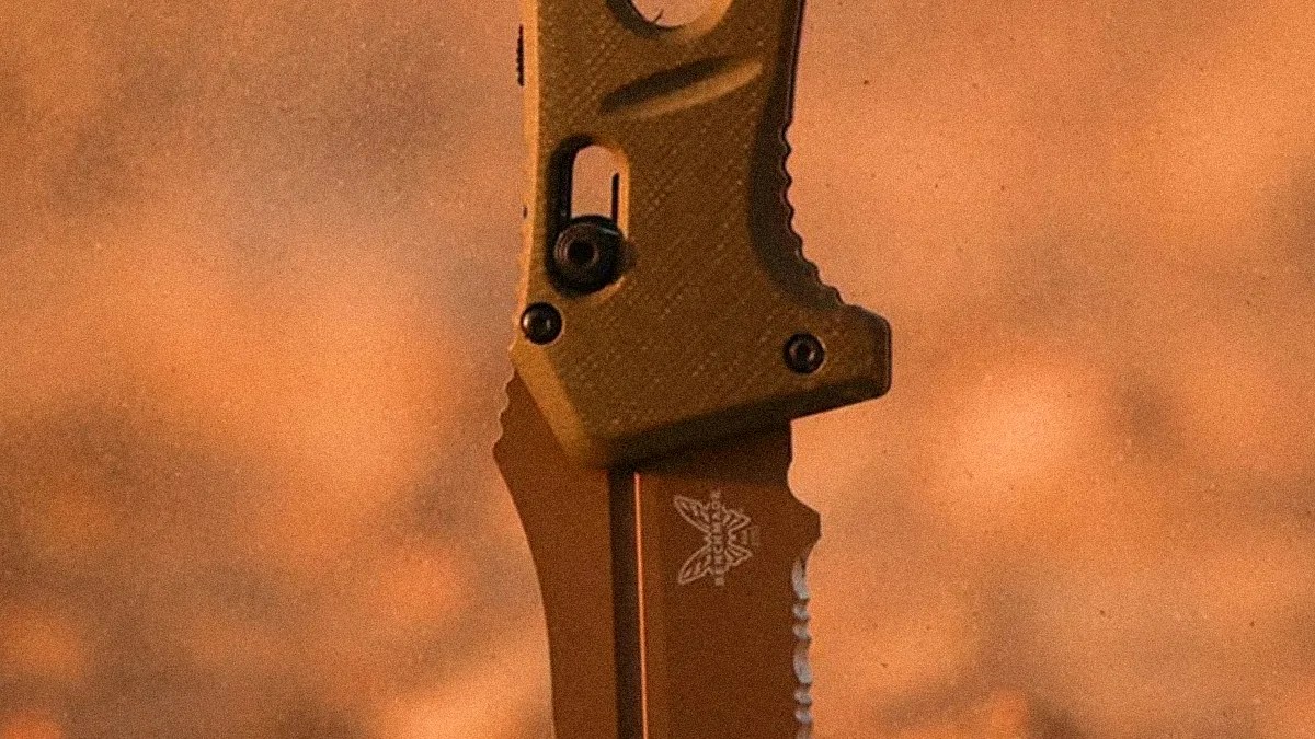 Close-up of a partially serrated brown folding knife blade with a butterfly logo on the blade and a textured handle.