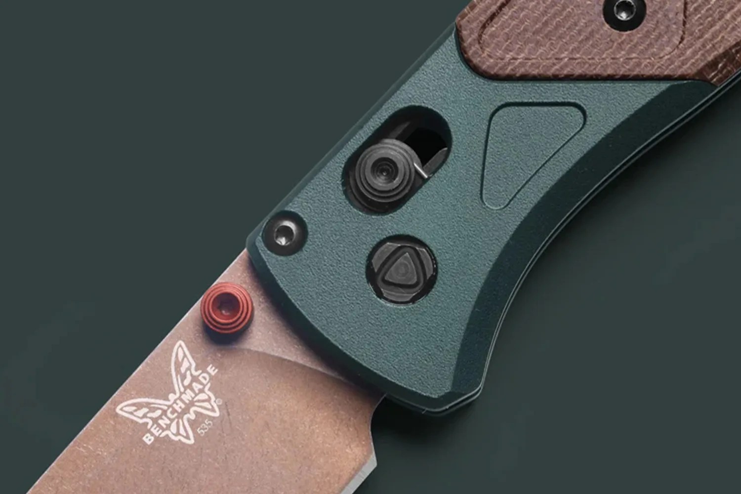 Close-up of a Benchmade folding knife blade with a copper finish and a green textured handle.
