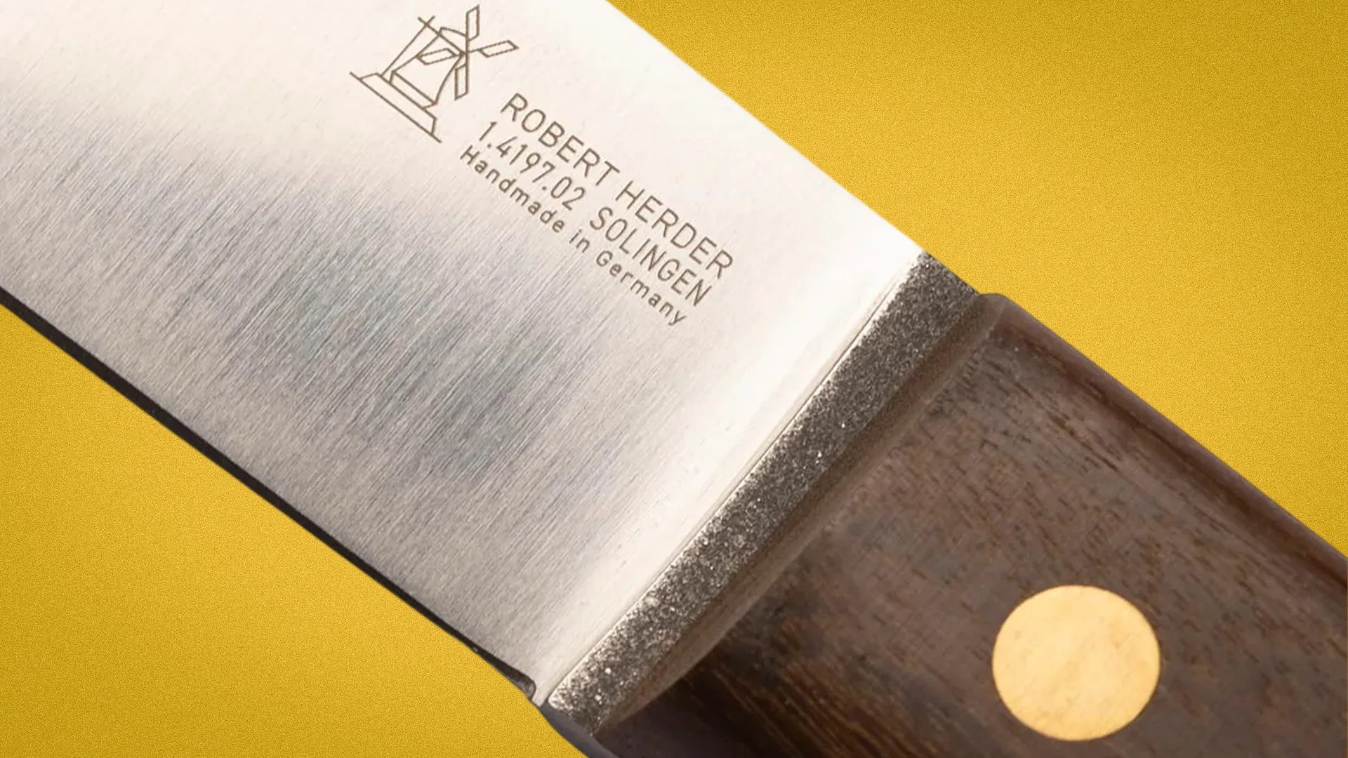 Close-up of a Robert Herder Solingen knife blade with wooden handle and brass rivet on a yellow background.