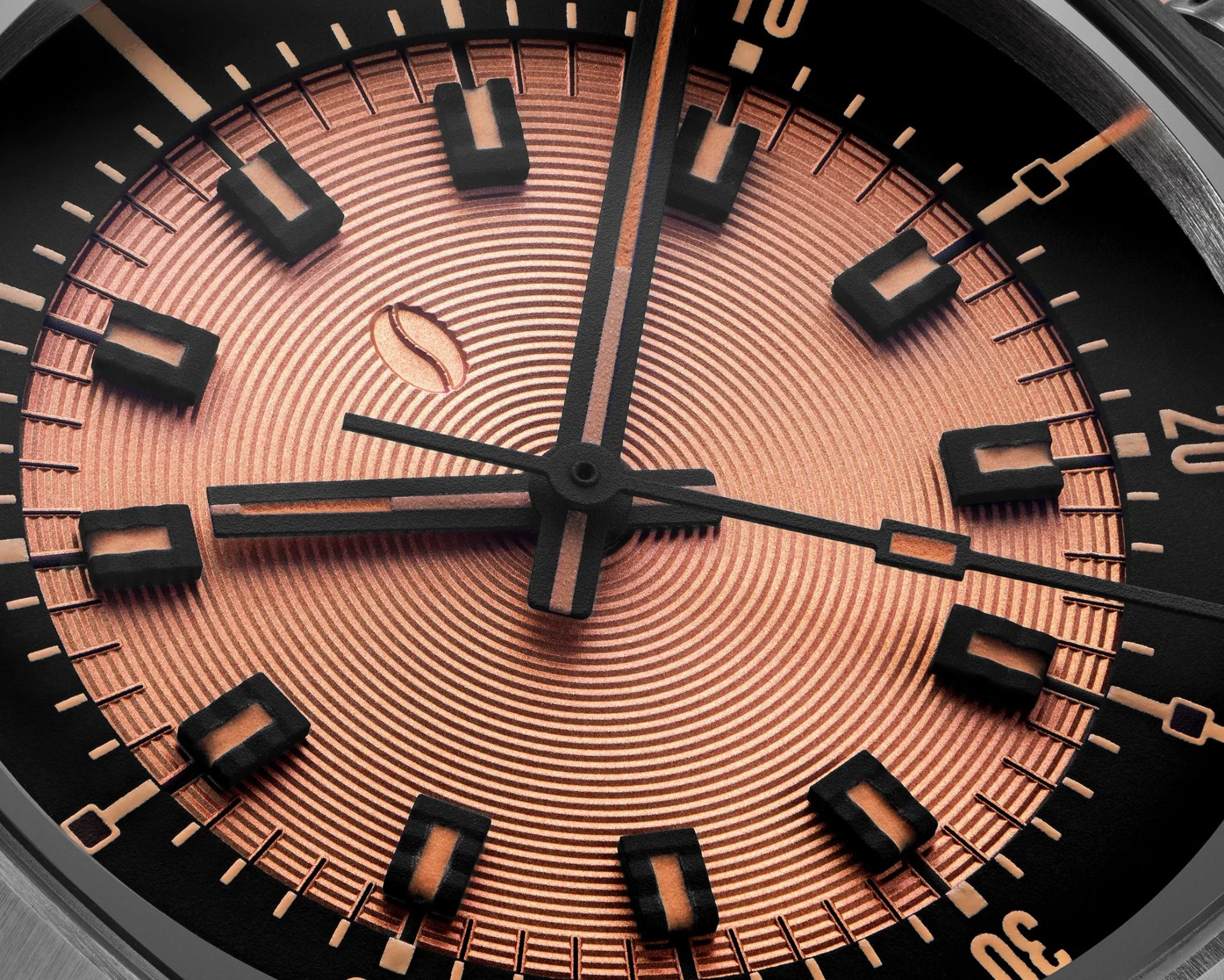 Close-up of a watch face with concentric circular pattern in copper tone and black rectangular hour markers.