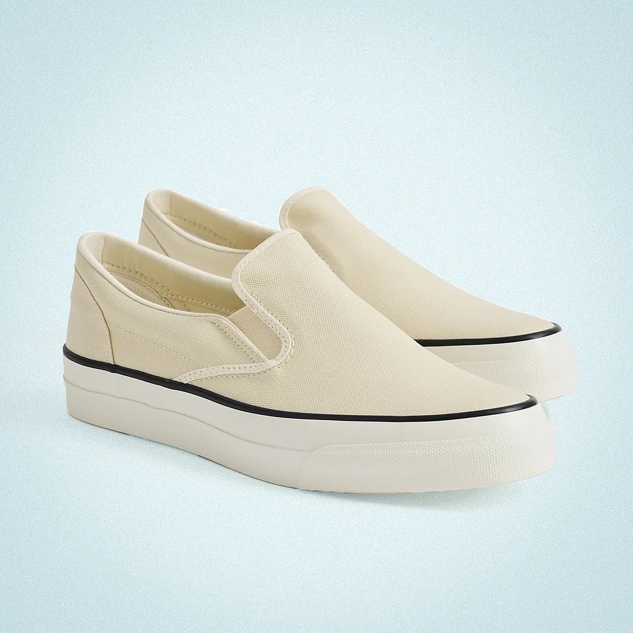 Pair of beige canvas slip-on sneakers with white rubber soles and black trim.