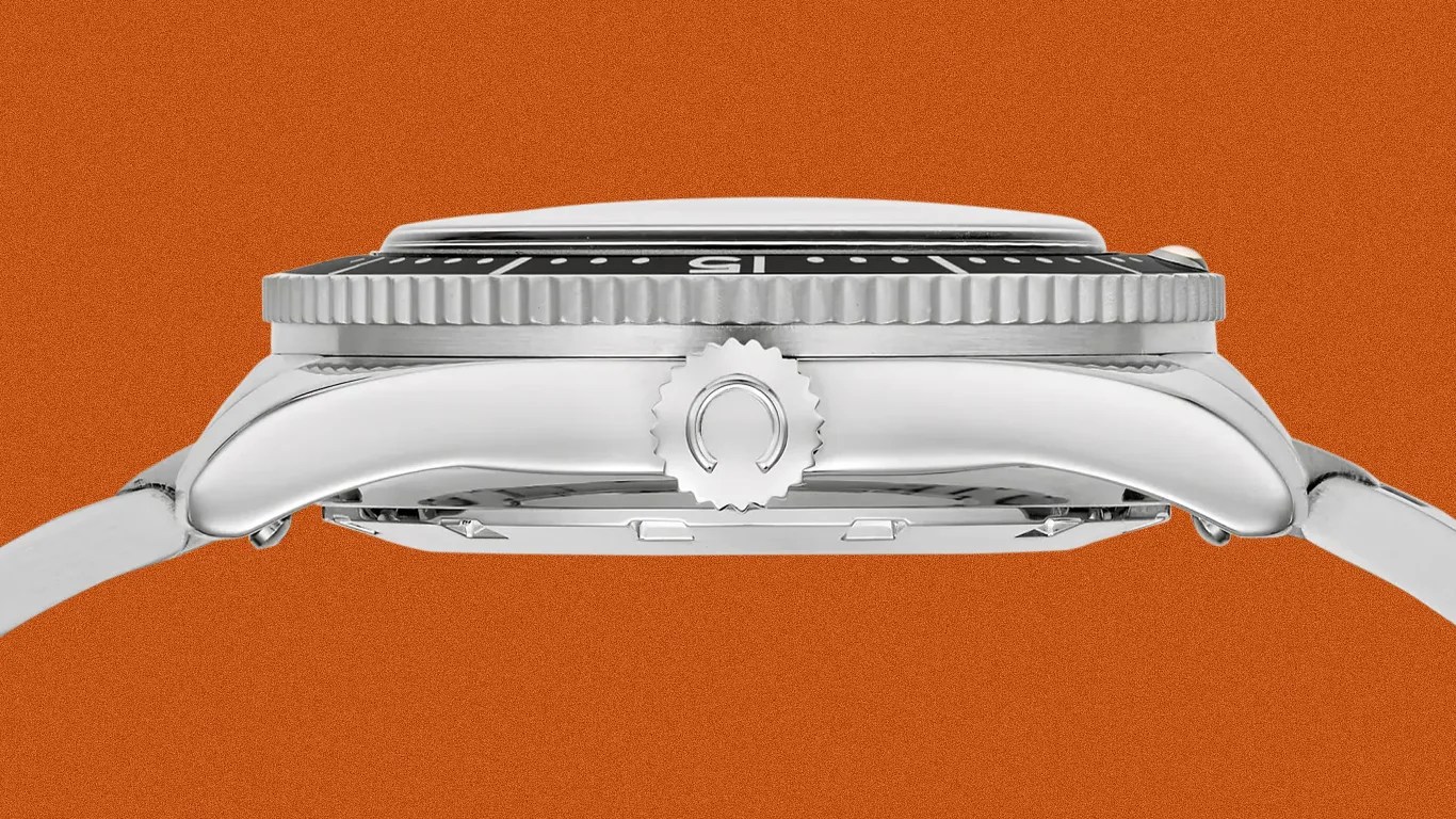 Side view of a silver metal watch case with a ridged bezel and a crown featuring a horseshoe-shaped logo.