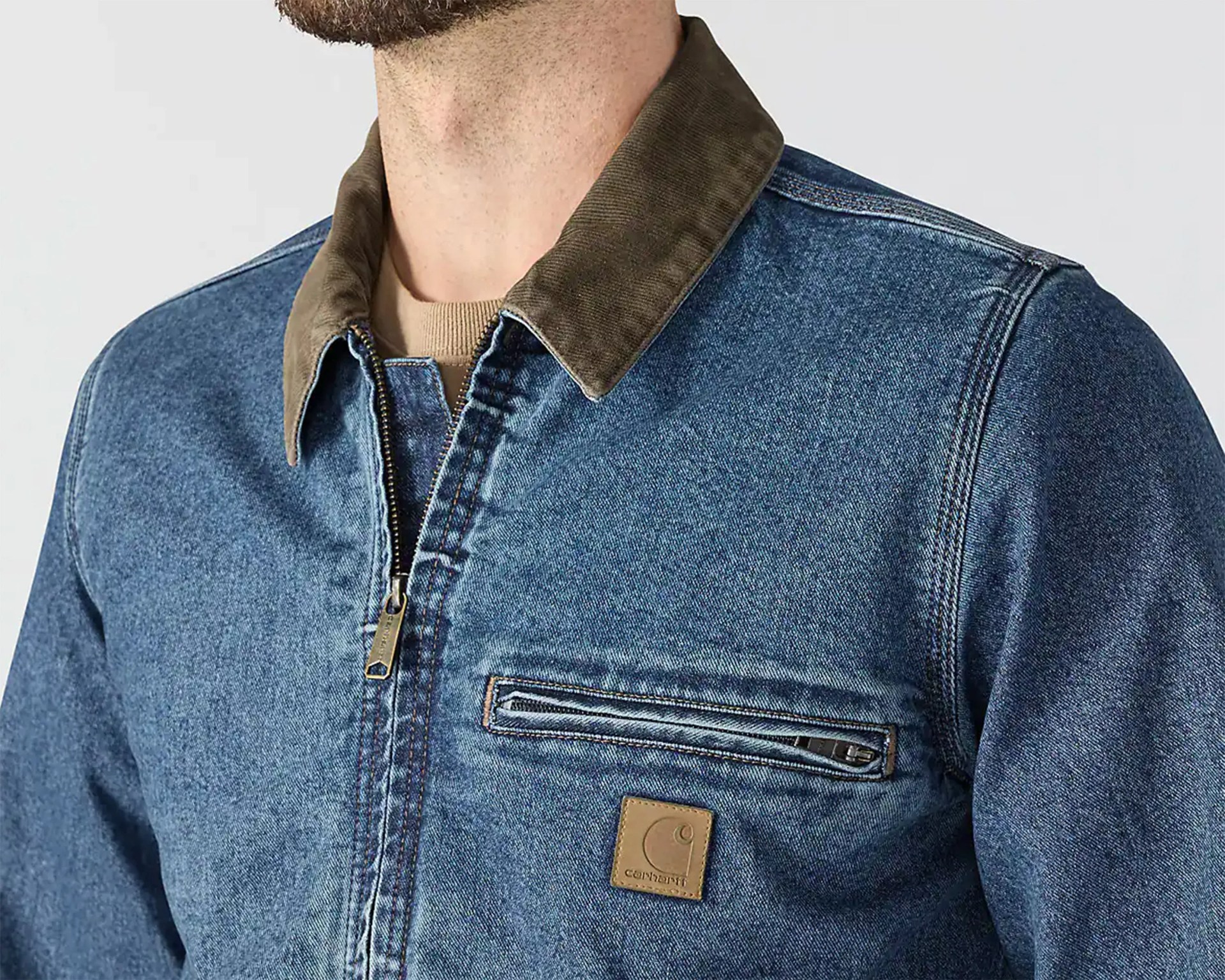 Blue denim jacket with brown corduroy collar, zippered chest pocket, and Carhartt logo patch.