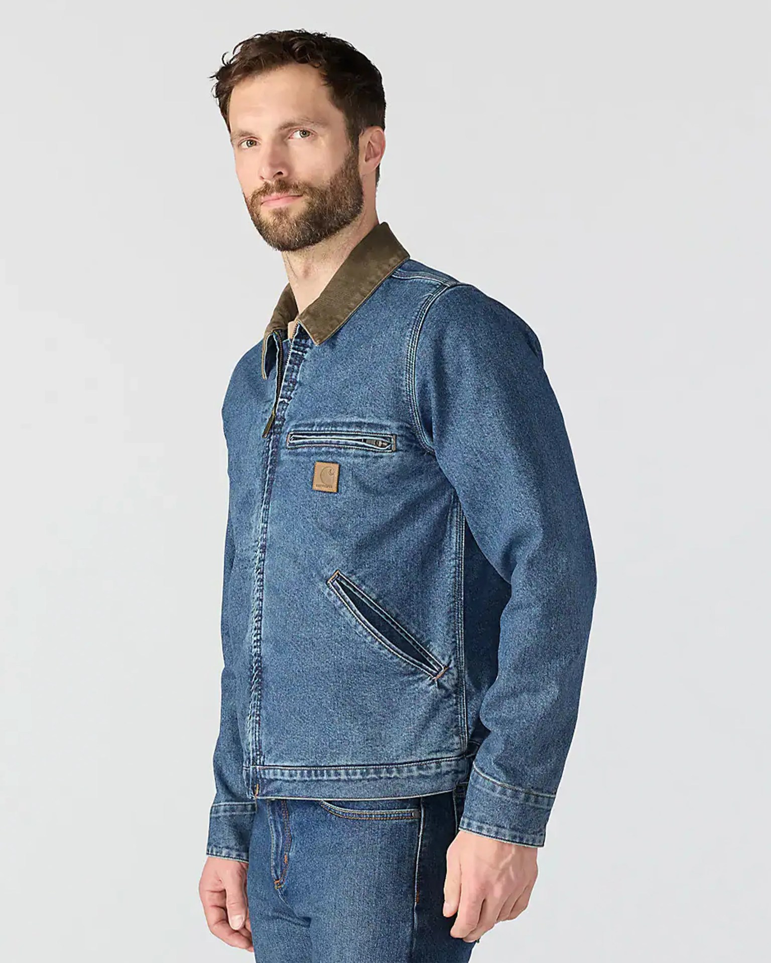 Man wearing a blue denim jacket with a brown collar and matching blue denim jeans.