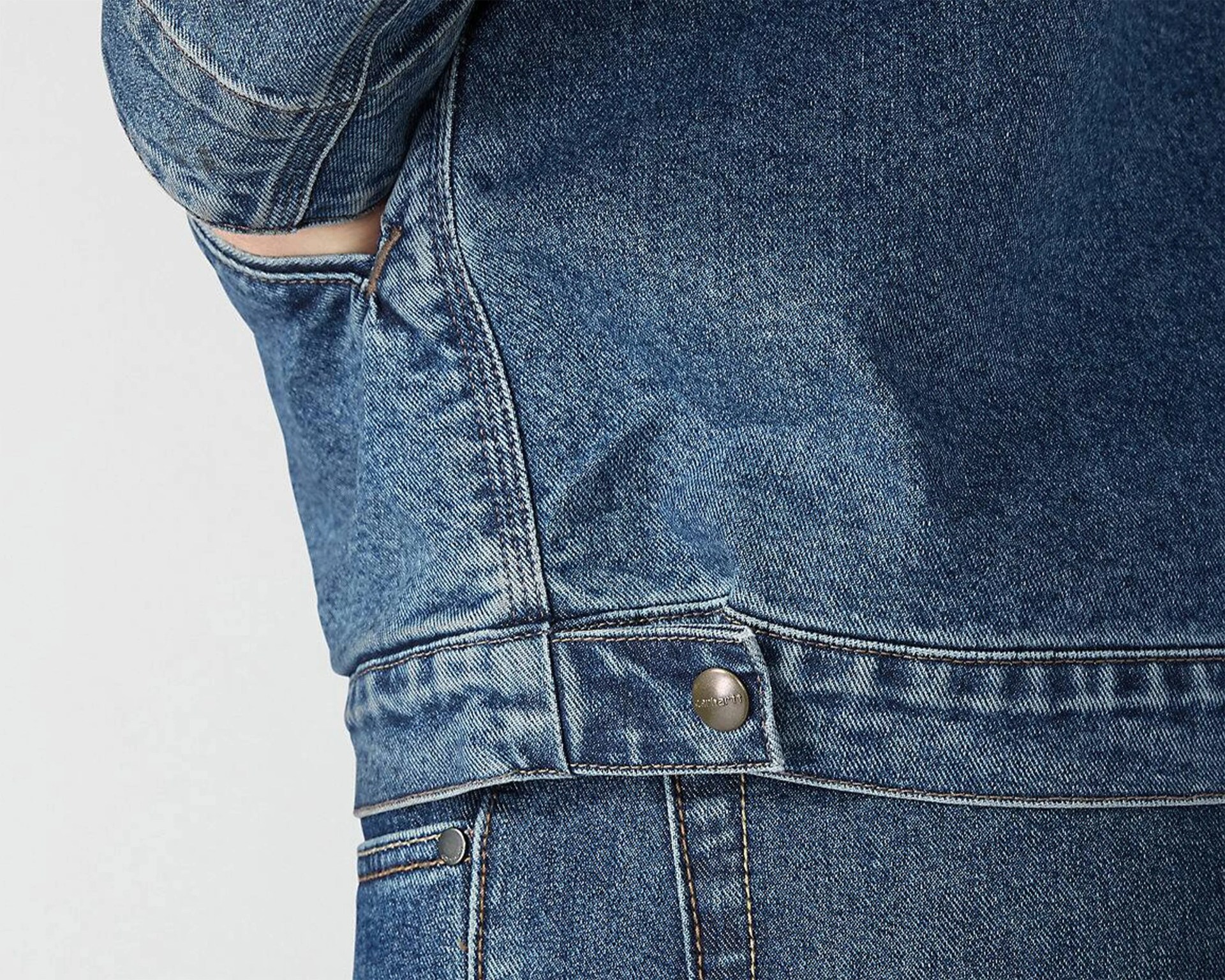 Close-up of blue denim jacket with visible stitching and metal button detail.
