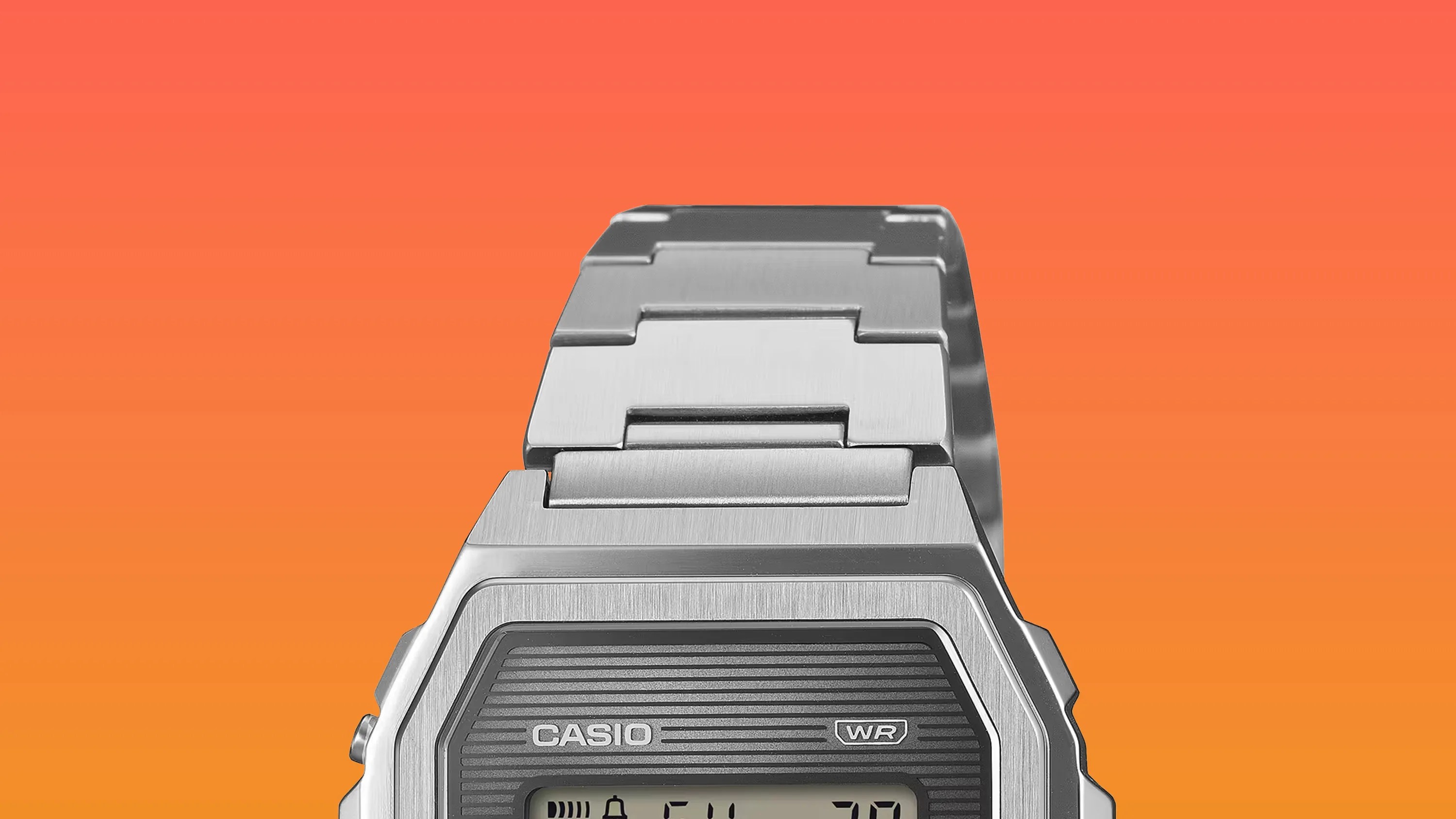 Silver metal Casio digital watch with a stainless steel link bracelet on an orange gradient background.