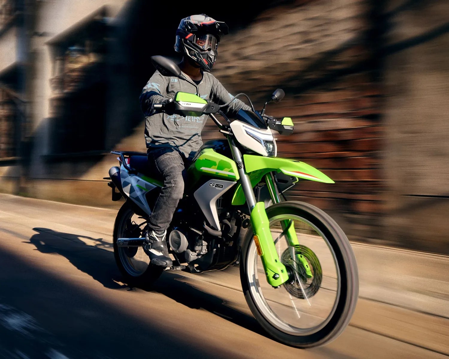 Person wearing a black helmet riding a green and white CF Lite motorcycle on a road.