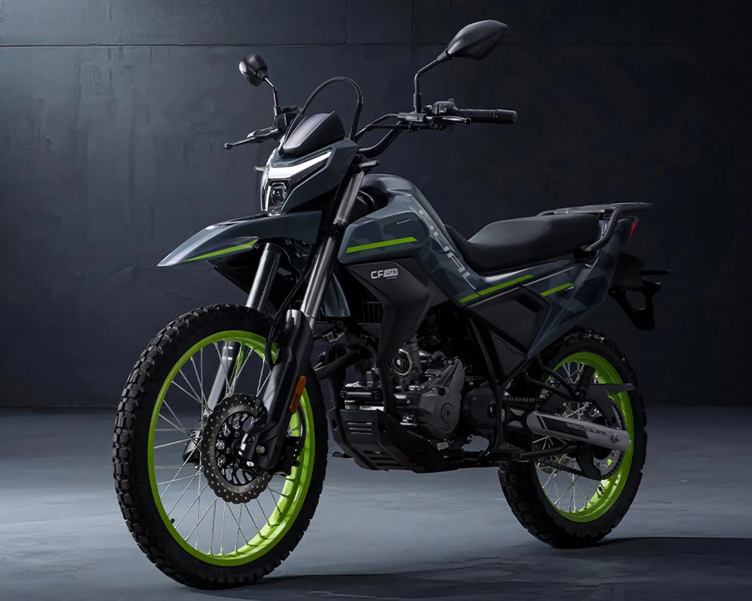 Dark gray dual-sport motorcycle with neon green wheel rims and black seat against a dark background.