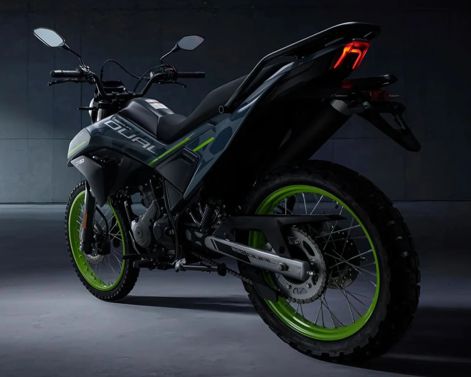 Black and gray dual-sport motorcycle with neon green rims and rear LED taillight in a dark setting.