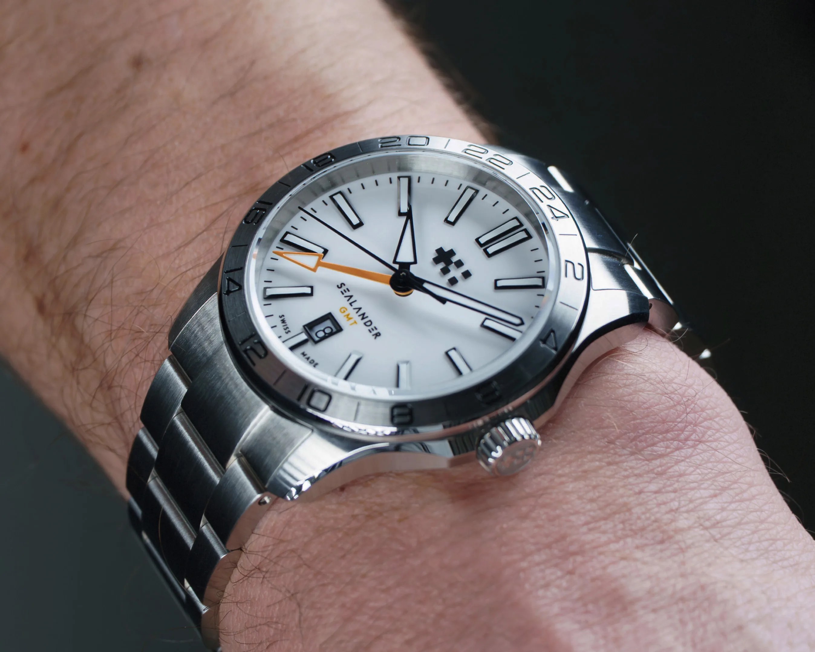 Silver Salander GMT wristwatch with white dial and orange GMT hand on a wrist.