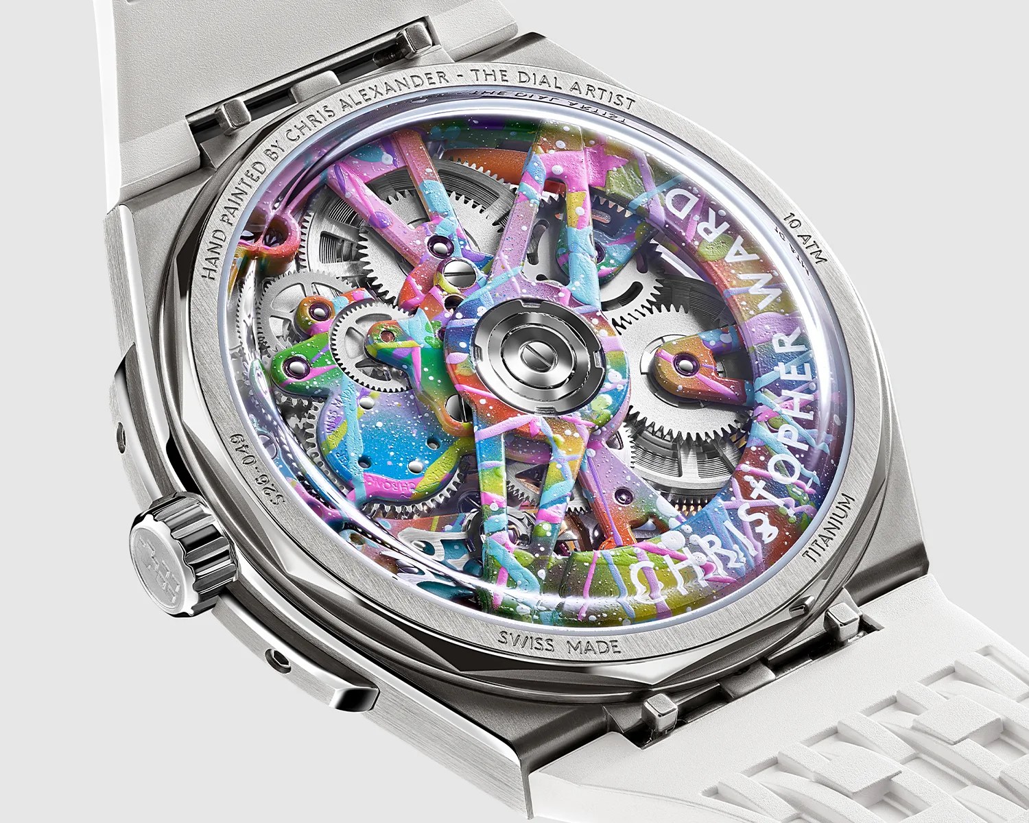 Close-up of a titanium watch back with colorful hand-painted gears and a white rubber strap.