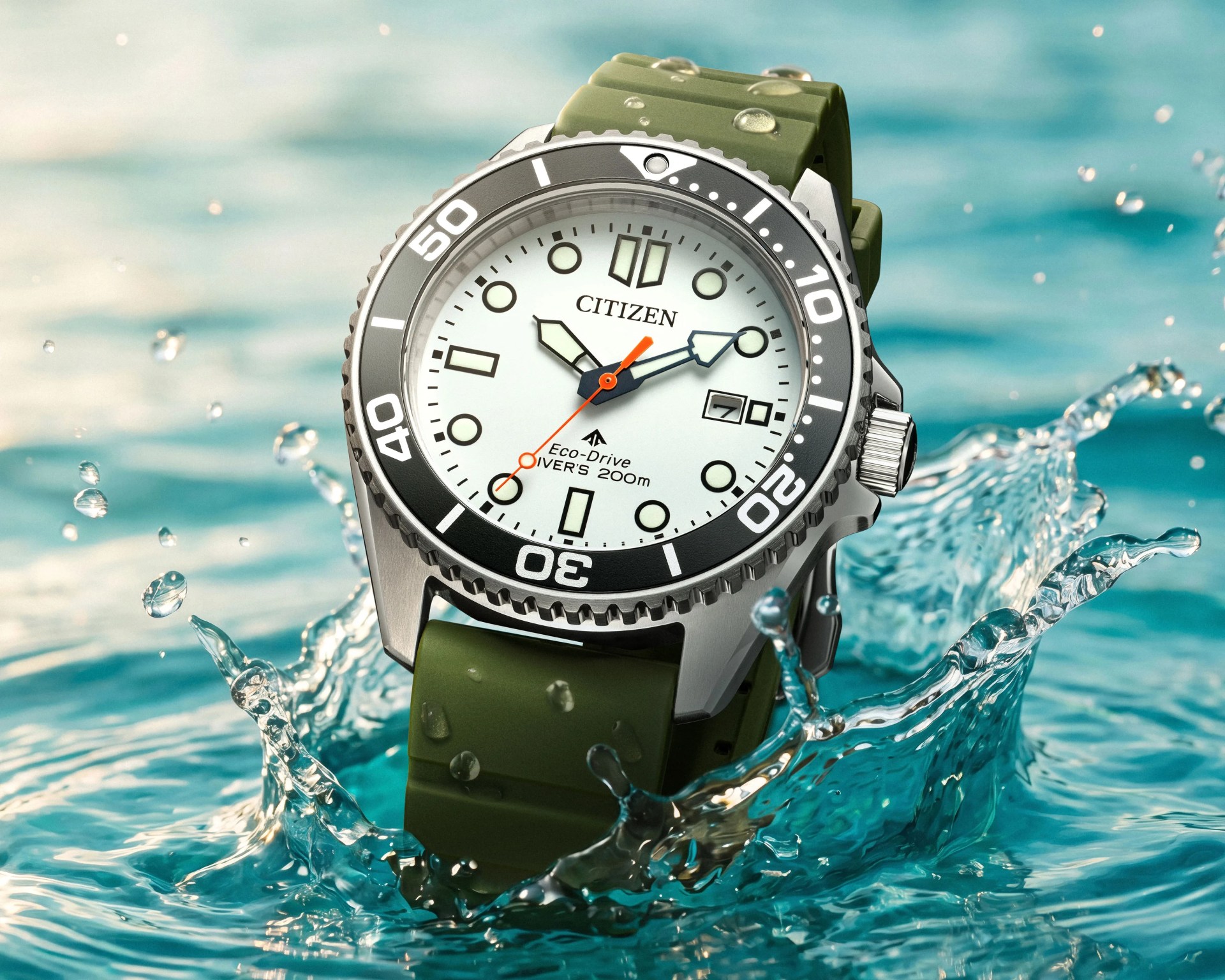 Silver Citizen Eco-Drive diver's watch with white dial, black bezel, and green rubber strap splashing in water.