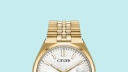 Gold metal link watch band attached to a gold watch case with a white textured dial.