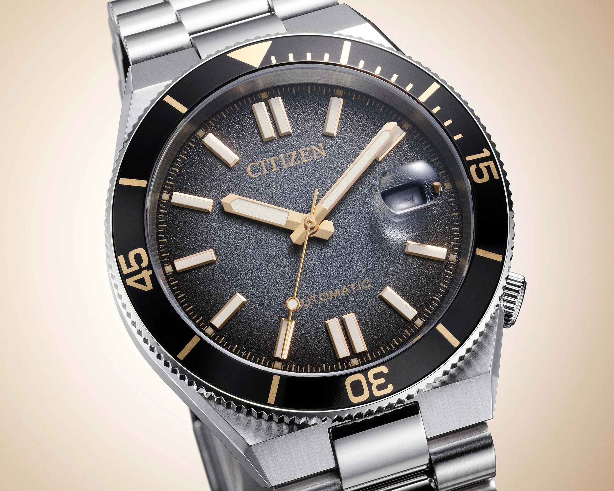 Close-up of a Citizen automatic watch with a textured black dial, gold-tone markers, and a stainless steel bracelet.
