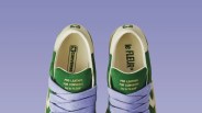 Pair of green and white Converse Pro Leather sneakers with lavender laces on a purple background.