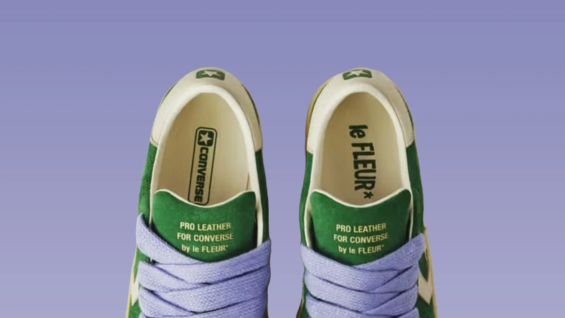 Pair of green and white Converse Pro Leather sneakers with lavender laces on a purple background.