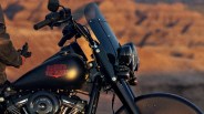 Black Harley-Davidson motorcycle fuel tank with red logo and tall windshield in desert setting.