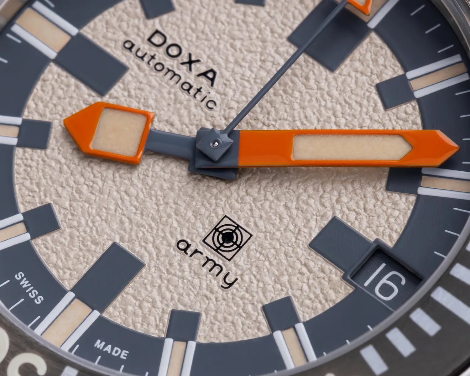Close-up of a DOXA automatic watch face with textured beige dial, orange and gray hands, and date window showing 16.