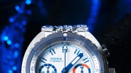 Close-up of a silver DOXA T. GRAPH II watch with blue and orange details and water droplets on the bezel.