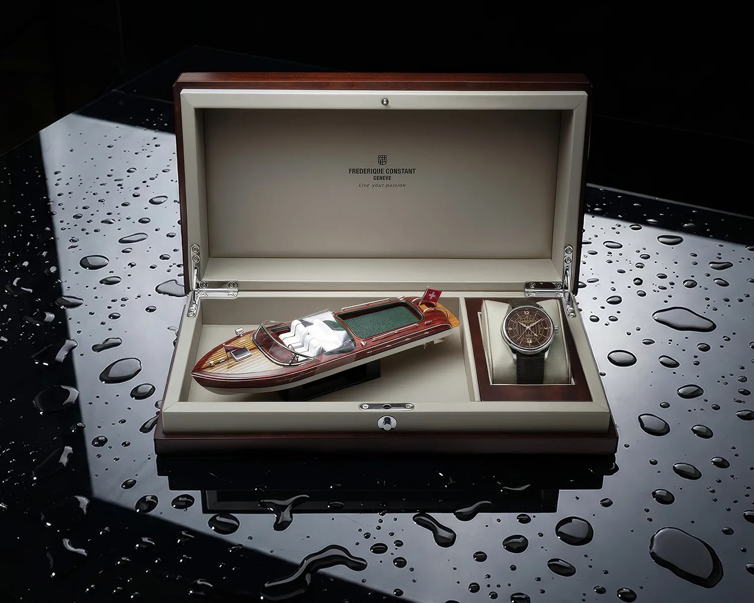 Open wooden display box with a model wooden boat and a wristwatch with a brown dial and black leather strap.