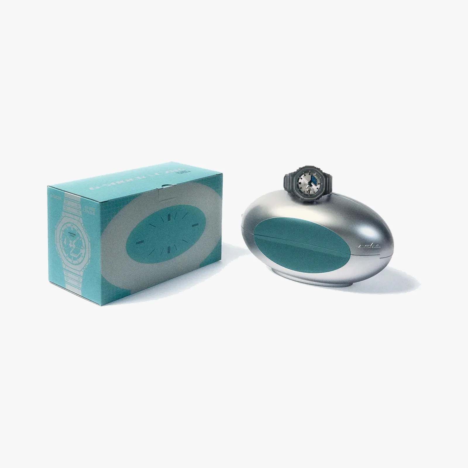 Silver oval-shaped watch case with teal accent and a black wristwatch on top, next to a teal box with watch illustration.