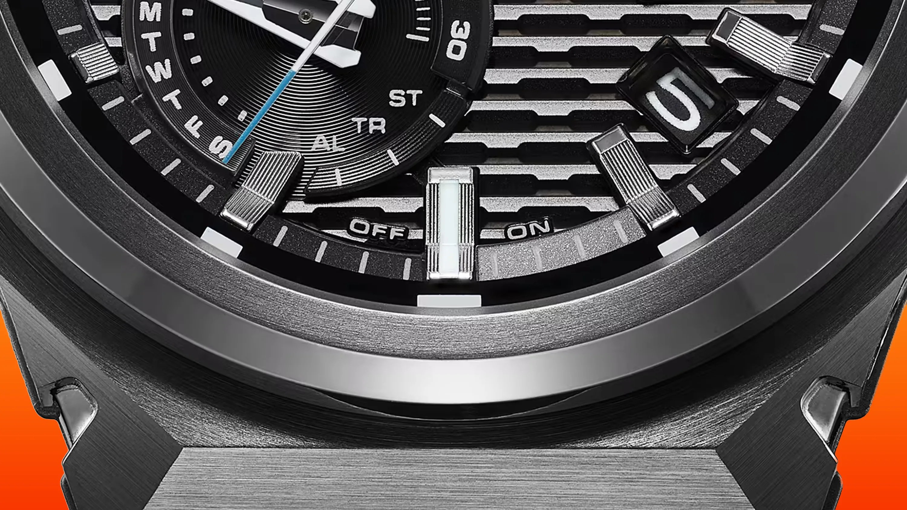 Close-up of a black and silver watch face showing day indicators, a date window displaying "5," and an "OFF" and "ON" switch indicator.