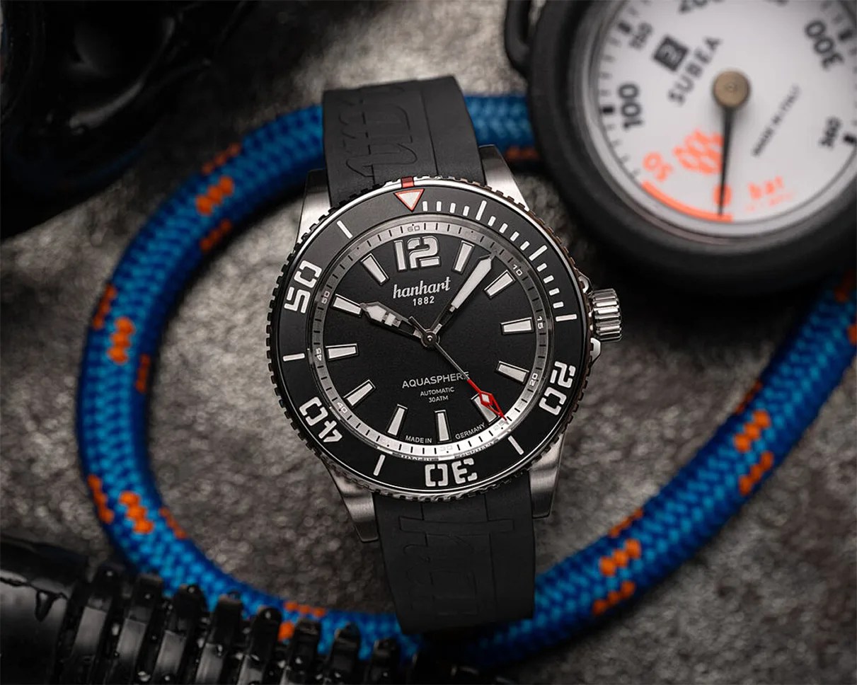 Black Hanhart Aquasphere dive watch with silver bezel and black rubber strap on a textured surface with blue and orange rope.