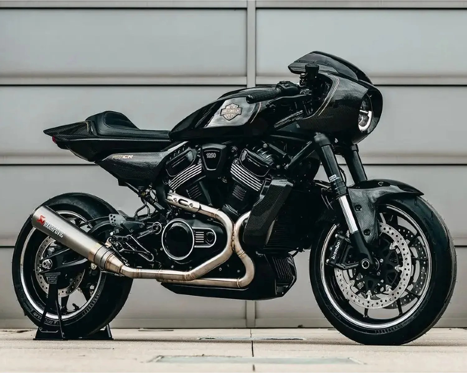 Black Harley-Davidson motorcycle with carbon fiber bodywork and Akrapovic exhaust on a stand.