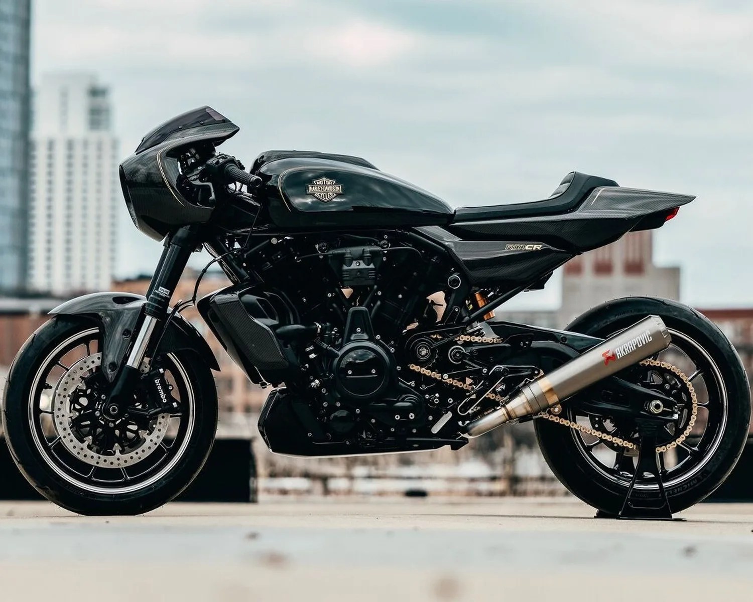 Black Harley-Davidson motorcycle with carbon fiber fairing and Akrapovic exhaust on a city rooftop.