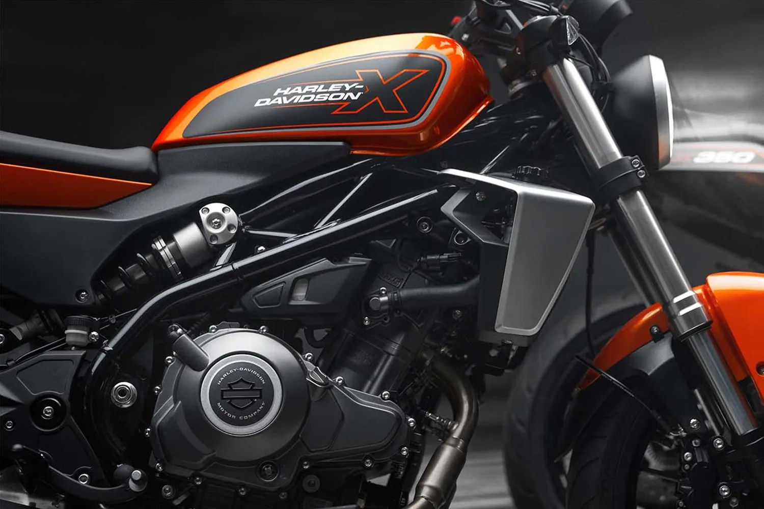 Close-up of an orange and black Harley-Davidson motorcycle engine and fuel tank with visible logo.